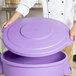 A chef places a purple Carlisle Bronco trash can lid on a purple container.