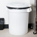 A Carlisle white flat round trash can lid on a white Carlisle trash can.