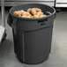 A Rubbermaid commercial trash can filled with potatoes.