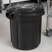 A black Rubbermaid BRUTE trash can with a plastic bag on it.