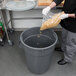 A man pouring food into a large gray Continental trash can.