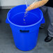 A man pouring grain into a blue Continental Huskee trash can.
