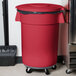 A red Carlisle Bronco trash can lid on a red trash can.