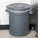 A Carlisle gray trash can lid on a gray trash can.