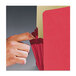 A hand opening a red Smead file pocket.