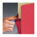 A hand opening a red Smead file pocket.