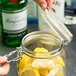 A person pouring lemon slices into an Anchor Hocking Hermes jar.