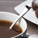 A cup of coffee with a Chef & Sommelier stainless steel demitasse spoon in it.