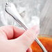 A hand holding a Libbey stainless steel teaspoon.