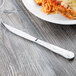 A silver Libbey steak knife on a wooden surface.