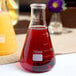 An American Metalcraft Erlenmeyer flask filled with red liquid on a table in a brunch café.