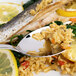 A plate of fish and rice with a spoonful of food and a lemon wedge.