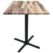 A Holland Bar Stool square rustic wood laminate table with a black cross base.