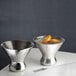 Two American Metalcraft stainless steel stemless martini glasses filled with a drink and oranges on a white surface.