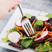 A Libbey heavy weight stainless steel salad fork in a salad with radishes and carrots.