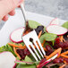 A Libbey stainless steel salad fork in a salad with radishes and carrots.