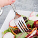 A Libbey stainless steel salad fork in a salad with carrots and radishes.