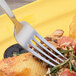 An Arcoroc stainless steel dinner fork on a plate of food.