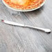 A pie on a plate next to a Libbey stainless steel utility knife.