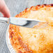 A hand using a Libbey stainless steel utility knife to cut a pie.