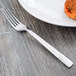 A Libbey stainless steel dinner fork on a plate with food.