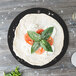 An Epicurean Richlite wood fiber pizza board with a pizza topped with tomatoes and basil.