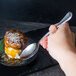 A hand holding a Libbey stainless steel dessert spoon over a dessert.
