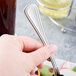 A person holding a Libbey Masterpiece stainless steel salad fork.