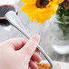 A hand holding a Libbey stainless steel utility/dessert fork.