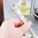 A hand holding a Libbey Kings stainless steel salad fork with a silver handle.