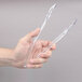 A hand holding a pair of clear plastic tongs.