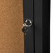 An Aarco black indoor lighted bulletin board cabinet with a key in the lock.