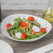 A Schonwald white porcelain bowl filled with a salad with tomatoes, radishes, and spinach.