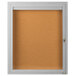 A white framed enclosed bulletin board with a key.
