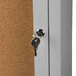 The key is in the lock of a satin anodized Aarco enclosed bulletin board cabinet.