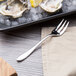 A Chef & Sommelier stainless steel oyster fork on a plate of oysters.