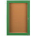 An Aarco green powder coated enclosed bulletin board cabinet with a cork board and glass door with a key.