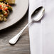 A Chef & Sommelier stainless steel teaspoon on a plate of food.