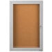 A white satin anodized enclosed bulletin board cabinet with a door and key.