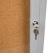 A satin anodized indoor bulletin board with a cork board door and key lock.