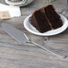 A slice of chocolate cake on a plate with an Arcoroc stainless steel cake server next to a knife.