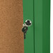 A key in a keyhole unlocking a green Aarco indoor bulletin board cabinet.