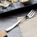 A Chef & Sommelier stainless steel oyster fork on a plate of ice and oysters.