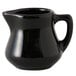 A black Tuxton creamer pitcher with a handle.