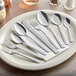 A plate with silverware including Choice Dominion stainless steel iced tea spoons and forks.