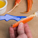 A person using a Choice Shuckaneer blue seafood sheller to remove a crab claw.