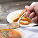 A person using a Chef & Sommelier stainless steel soup spoon to eat soup.