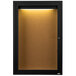 A black framed cabinet door with a light on a cork board.