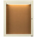 An ivory powder coated enclosed bulletin board cabinet with lights on the inside.