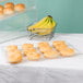 A Cal-Mil shallow clear bakery tray holding doughnuts and bananas on a bakery display counter.